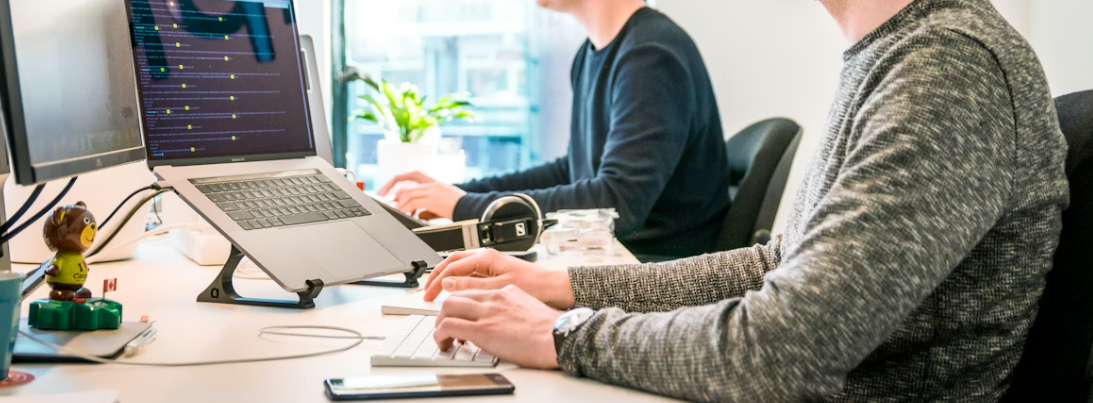 Two people working on laptops at a shared desk