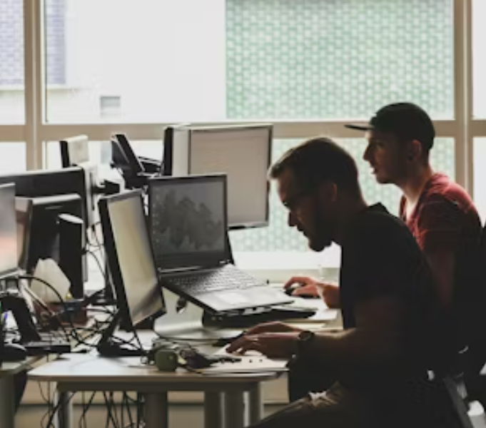 Two developers working at several computers by a window