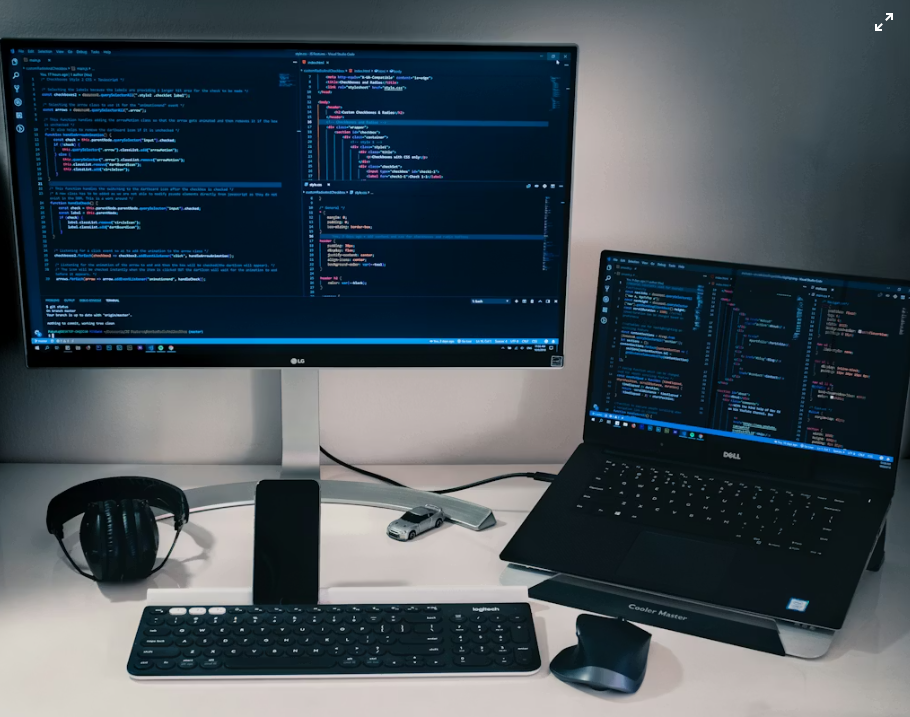 A monitor and a laptop showing code on a desk